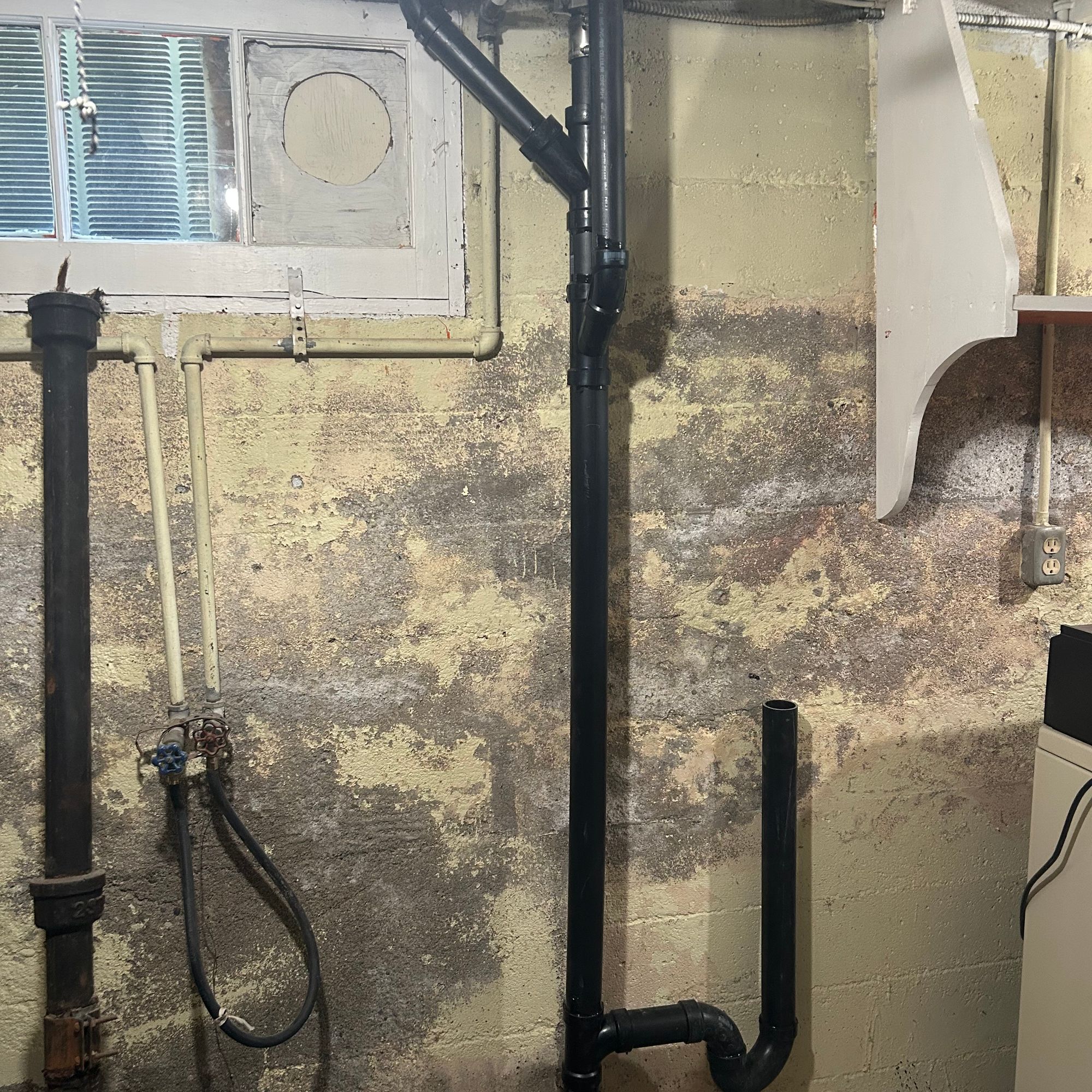 Exposed plumbing beneath a window